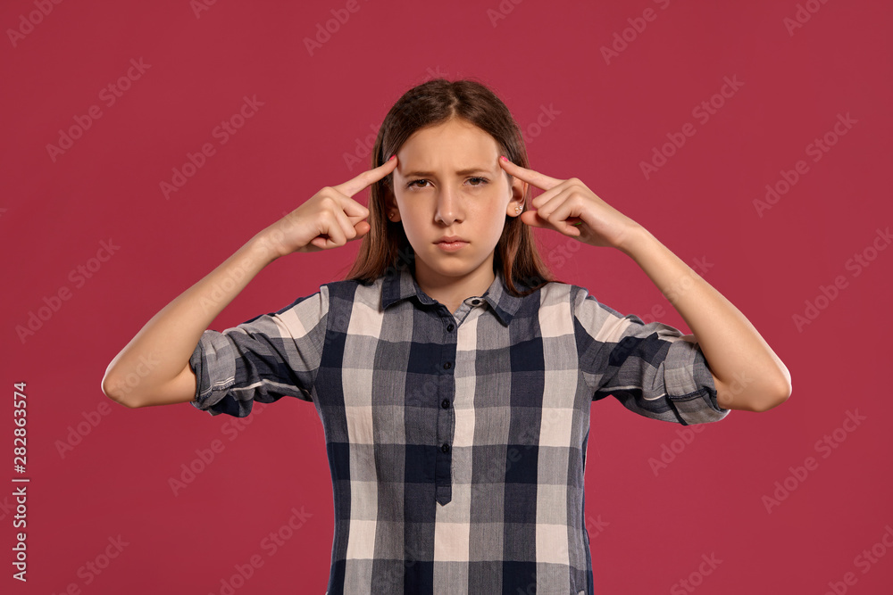 Beautiful teenage girl in a casual checkered shirt is posing against a pink studio background. Beautiful teenage girl in a casual checkered shirt is posing against a pink studio background.