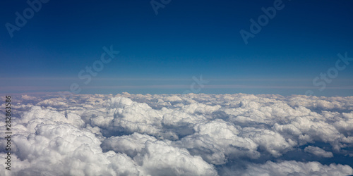 Blue sky and fluffy clouds. View out of a plane window.