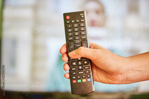 young girl watching tv and holding a remote control from tv