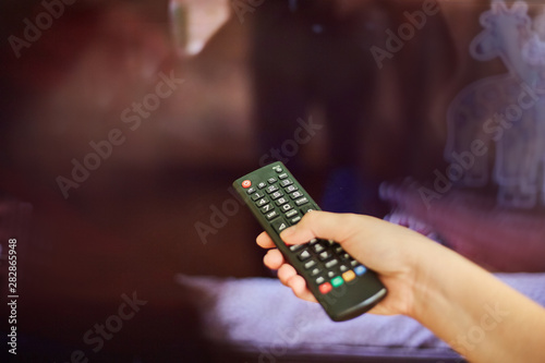 young girl watching tv and holding a remote control from tv