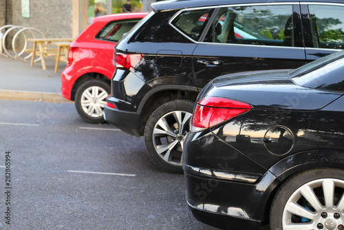 Closeup of rear, back side of black car with  other cars parking in outdoor parking area. © Amphon