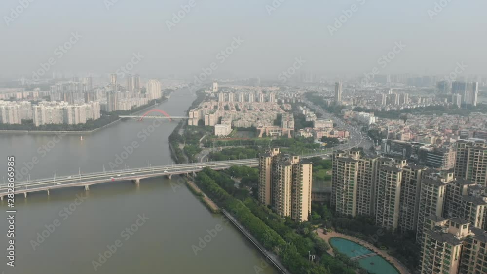 We see a river that bifurcates. The bridge over the river on which the active movement of cars goes deep into the city. On the shore there is an residential complex with identical houses and a pool. We see a river that bifurcates. The bridge over the river on which the active movement of cars goes deep into the city. On the shore there is an residential complex with identical houses and a pool.