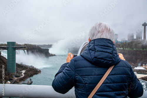 Tourist using a set of binoculars pointing at Niagara falls