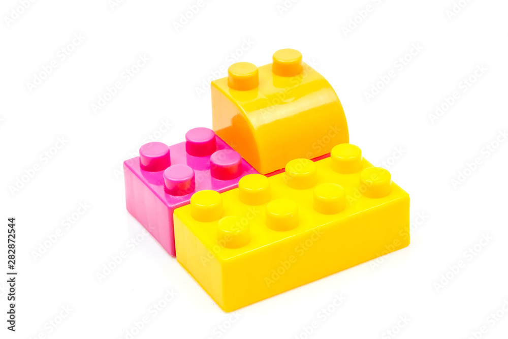 Fototapeta premium Pink and yellow plastic building block isolated on white background. Developmental toys for children.
