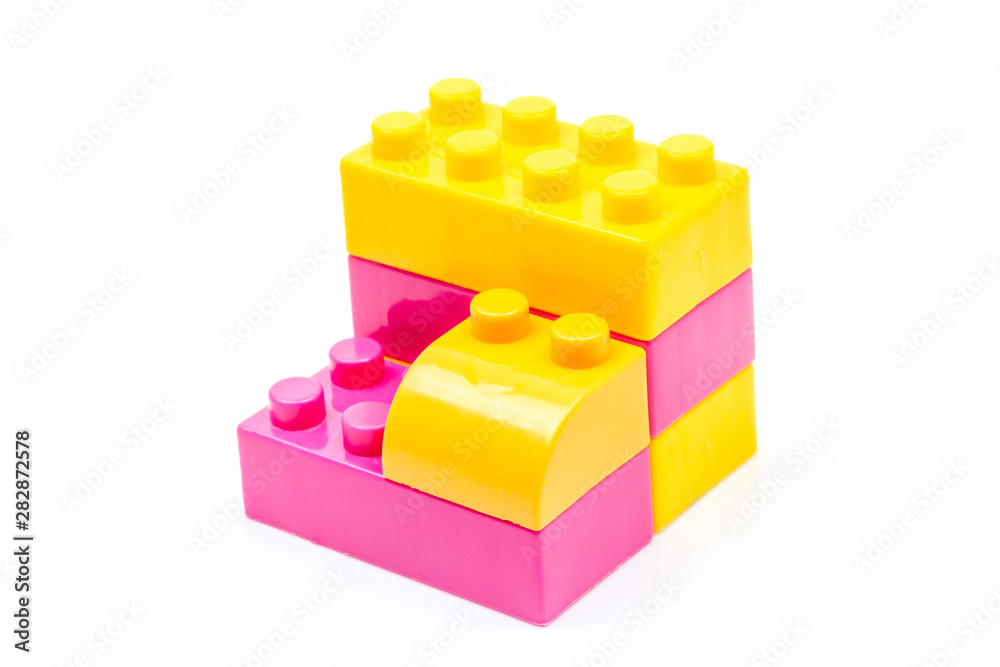 Fototapeta premium Pink and yellow plastic building block isolated on white background. Developmental toys for children.