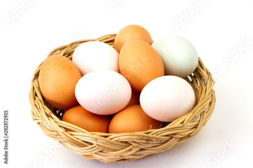 Fresh brown and white eggs in basket isolated on white background.