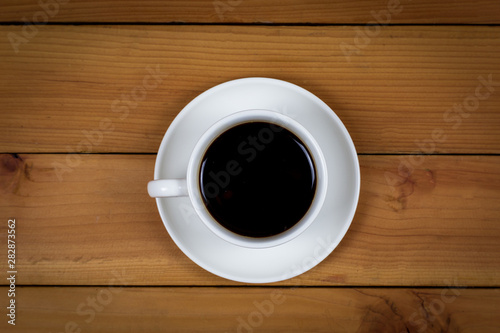 Cup of coffee on wood background, top view.