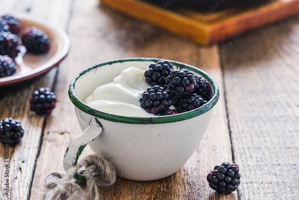Morning meal, yogurt, fresh summer blackberries in rural mug Morning meal, yogurt, fresh summer blackberries in rural mug
