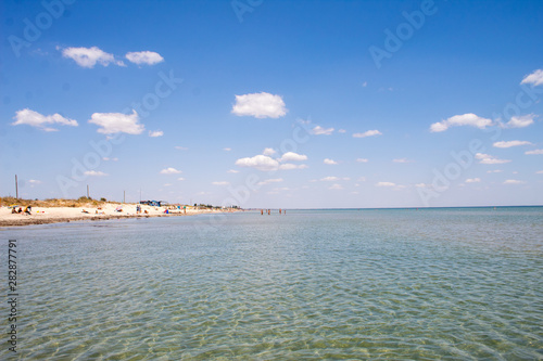 Summer beautiful seascape - transparent sea with a sandy bottom and blue sky, summer breeze.