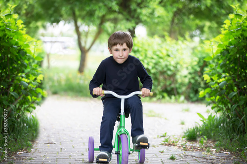 The boy on a tricycle.Child preschooler spin the pedals on a toy bicycle