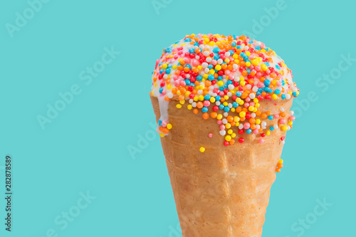 Ice cream cone close up. White ice cream scoop in a waffle cone on a blue background. Sweet dessert decorated with multicolored sprinkles