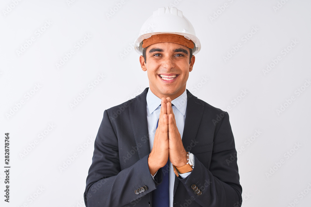 Young handsome architect man wearing suit and helmet over isolated white background praying with hands together asking for forgiveness smiling confident. Young handsome architect man wearing suit and helmet over isolated white background praying with hands together asking for forgiveness smiling confident.