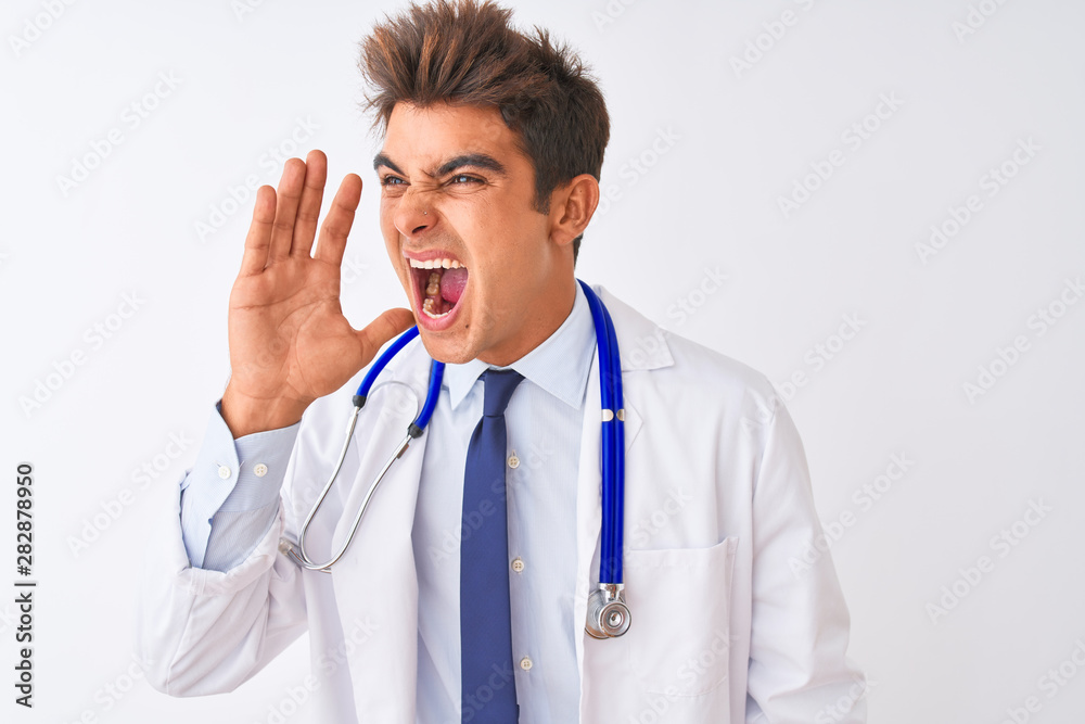 Young handsome doctor man wearing stethoscope over isolated white background shouting and screaming loud to side with hand on mouth. Communication concept.