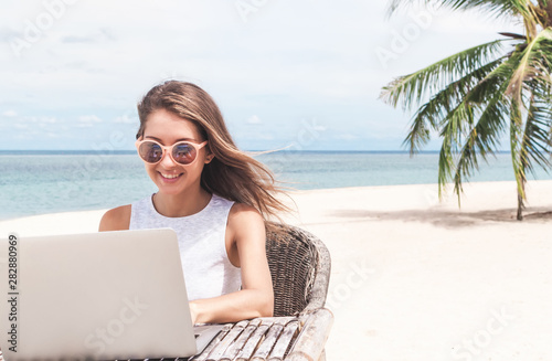 Young woman using laptop computer on a beach. Freelance concept