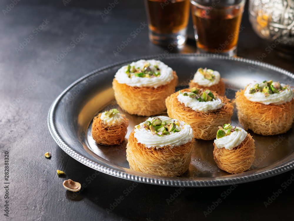 Kataifi, kadayif, kunafa, baklava pastry nest cookies with pistachios with tea. Cooking sweets turkish, or arabic traditional ramadan pastry dessert on a dark background.