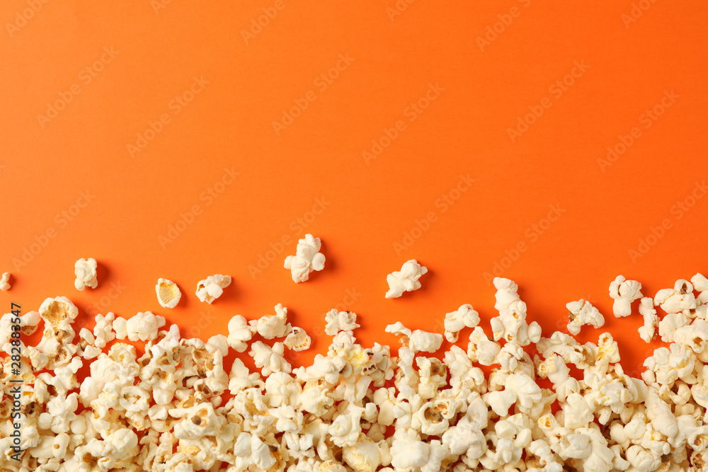 Flat lay composition with popcorn on orange background, copy space - obrazy, fototapety, plakaty 