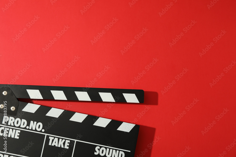Black clapperboard on red background, space for text