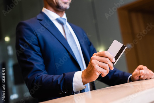 cropped view of businessman in suit giving credit card