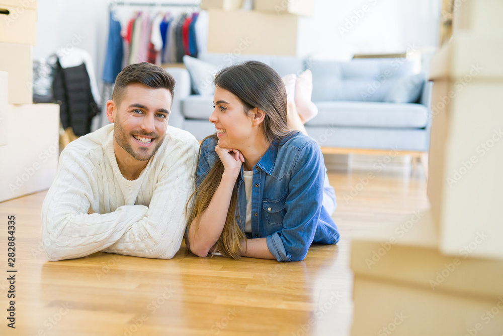 Young beautiful couple lying on the floor of new house, smiling in love very happy for moving to new apartment Young beautiful couple lying on the floor of new house, smiling in love very happy for moving to new apartment