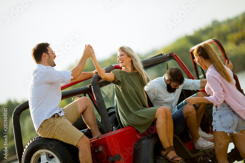 Group of young people  having fun by car outdoor at hot summer day © BGStock72