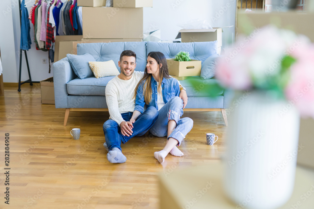 Young beautiful couple sitting on the floor of new apartment, smiling in love happy for moving to a new home Young beautiful couple sitting on the floor of new apartment, smiling in love happy for moving to a new home