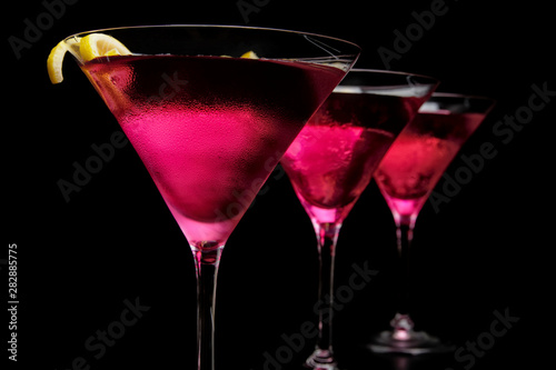 Three cosmopolitan cocktails in line on black counter