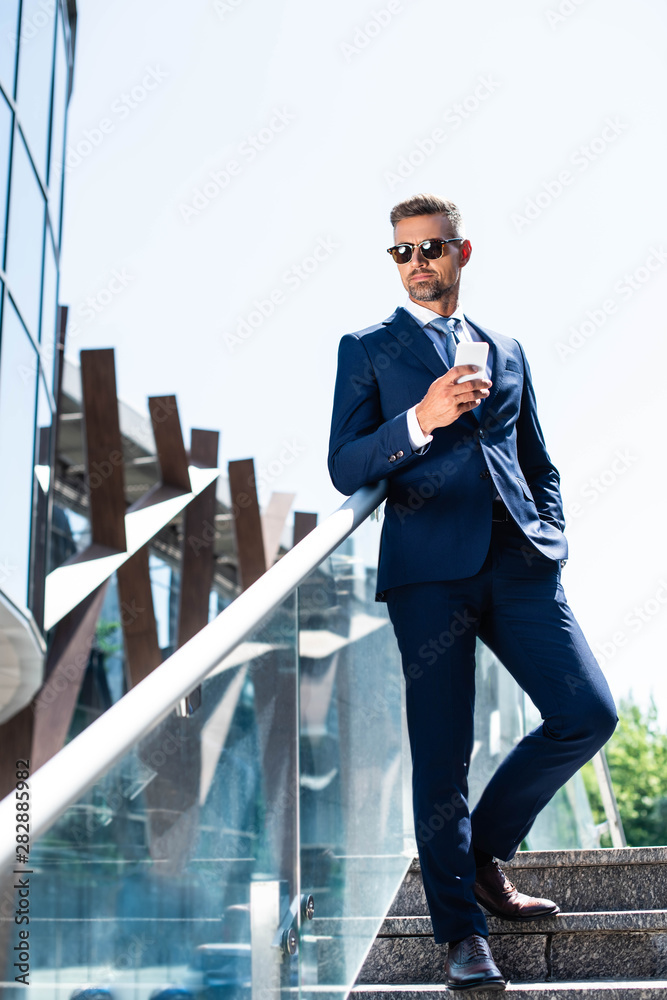 handsome man in suit with hand in pocket using smartphone handsome man in suit with hand in pocket using smartphone