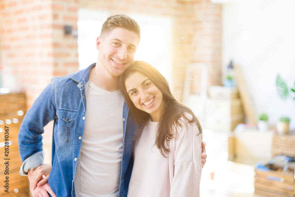 Beautiful young couple moving to a new home, standing on new aparment around cardboard boxes, hugging smiling happy and in love Beautiful young couple moving to a new home, standing on new aparment around cardboard boxes, hugging smiling happy and in love
