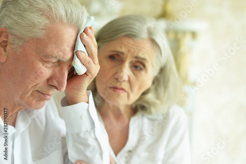 Sad senior couple at home, man with headache