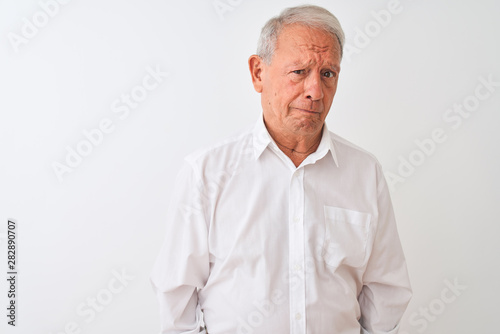 Senior grey-haired man wearing elegant shirt standing over isolated white background depressed and worry for distress, crying angry and afraid. Sad expression. © Krakenimages.com