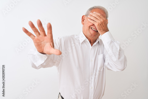 Senior grey-haired man wearing elegant shirt standing over isolated white background covering eyes with hands and doing stop gesture with sad and fear expression. Embarrassed and negative concept. © Krakenimages.com
