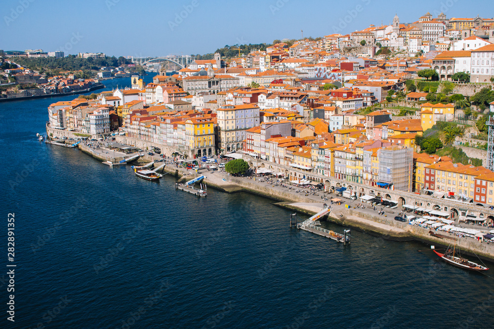 River Douro with embankment of Porto and boats. Porto panoramic landmark on sunny day. Old buildings with brick roofs by river Douro in Porto, Portugal. Historic district of Porto. Portuguese vacation
