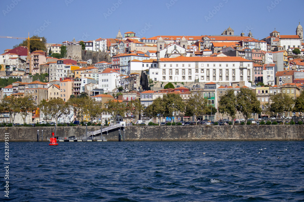 River Douro with colorful embankment of Porto. Porto panoramic landmark with boats on sunny day. Old buildings with brick roofs by river Douro in Porto, Portugal. Historic district of Porto. 