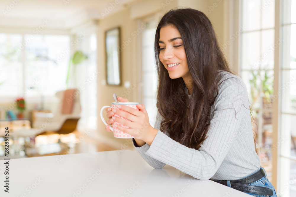 Beautiful young girl drinking a cup of coffee at home and smiling Beautiful young girl drinking a cup of coffee at home and smiling