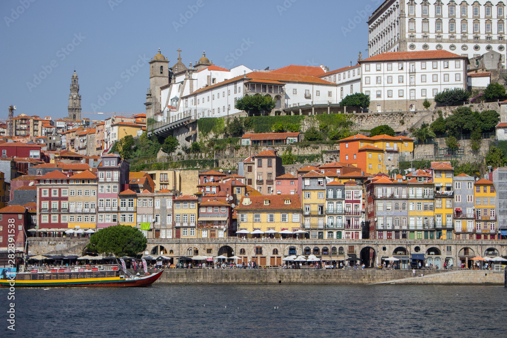 River Douro with colorful embankment of Porto. Porto panoramic landmark with boats on sunny day. Old buildings with brick roofs by river Douro in Porto, Portugal. Historic district of Porto. 