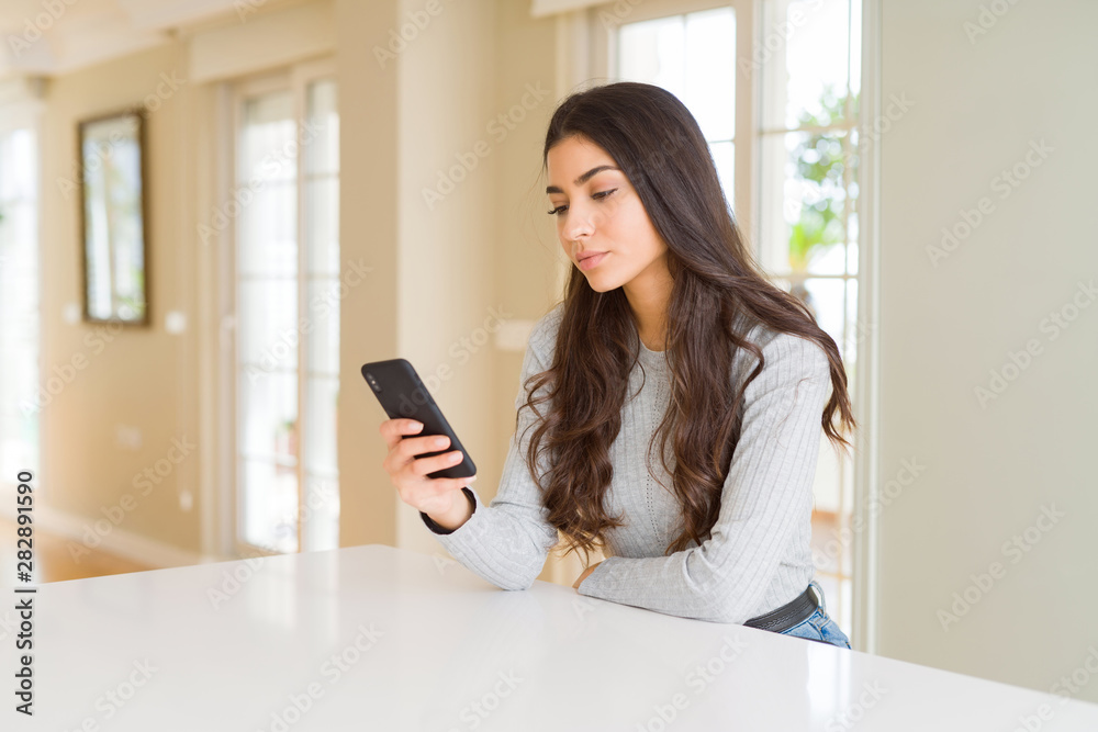 Young woman using smartphone sending a message with a confident expression on smart face thinking serious Young woman using smartphone sending a message with a confident expression on smart face thinking serious
