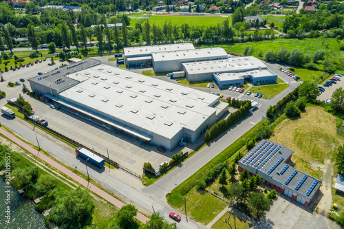 Aerial view of goods warehouse. Logistics center in industrial city zone from above. Aerial view of trucks loading at logistic center. View from drone.