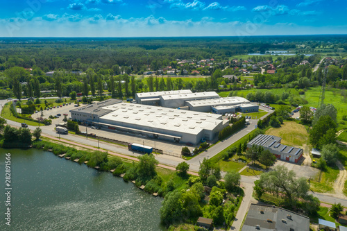 Aerial view of goods warehouse. Logistics center in industrial city zone from above. Aerial view of trucks loading at logistic center. View from drone.