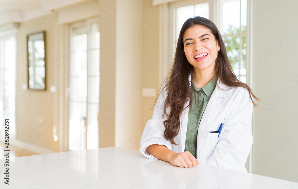 Young woman wearing medical coat at the clinic as therapist or doctor winking looking at the camera with sexy expression, cheerful and happy face. Young woman wearing medical coat at the clinic as therapist or doctor winking looking at the camera with sexy expression, cheerful and happy face.