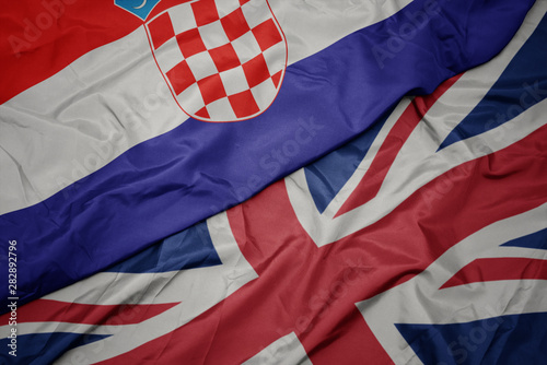 waving colorful flag of great britain and national flag of croatia.