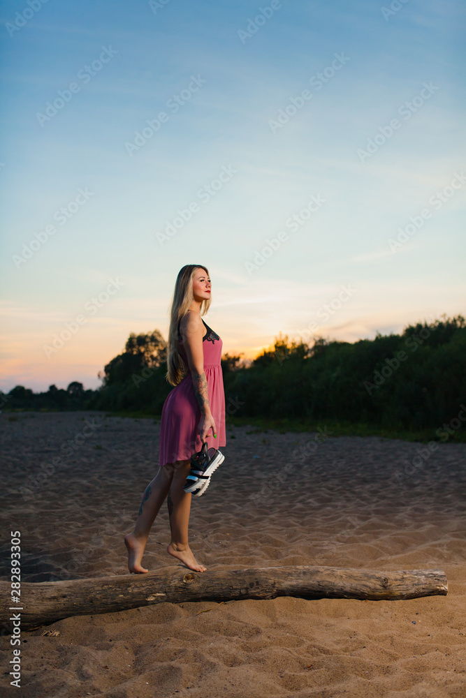 Beautiful blond model with long hair posing on the sand beach