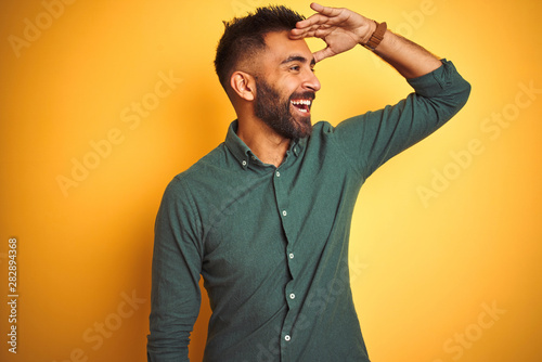 Fotografie Young indian businessman wearing elegant shirt standing over isolated white background very happy and smiling looking far away with hand over head
