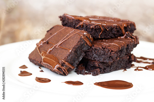Homemade brownie served with chocolate fudge. Sweet dessert on wooden background.