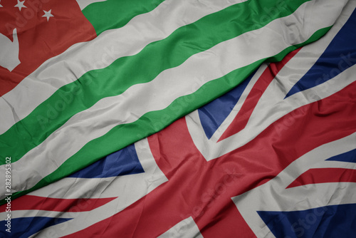 waving colorful flag of great britain and national flag of abkhazia.