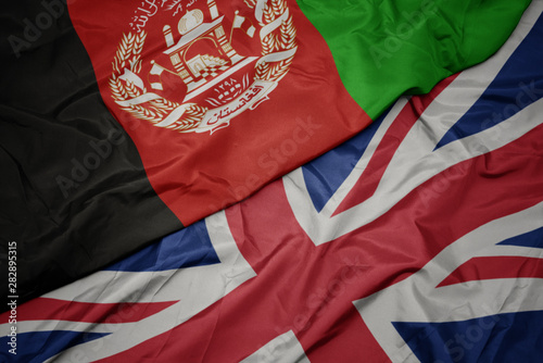 waving colorful flag of great britain and national flag of afghanistan.