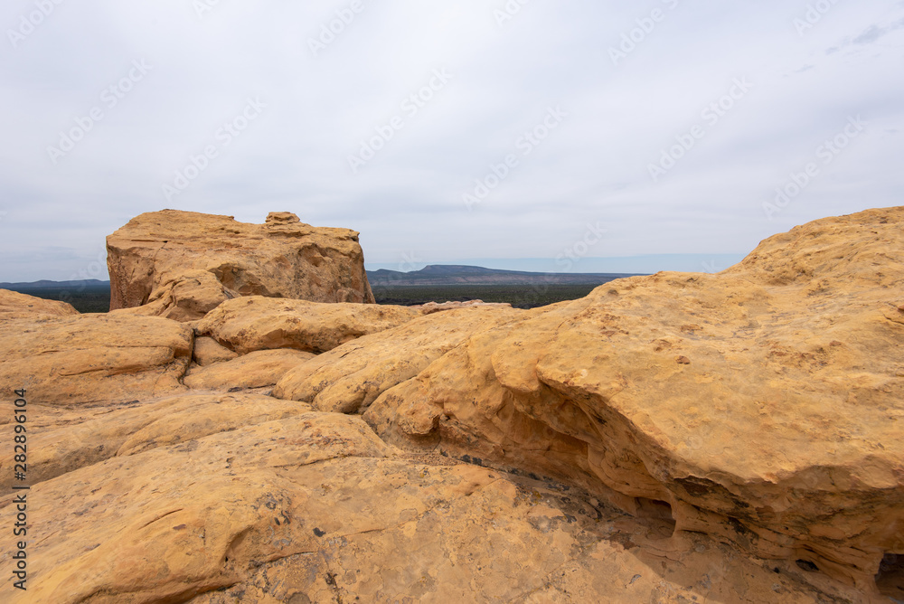 Landscape of yellow slick rock formations overlooking a valley at El Malpais National Monument in New Mexico