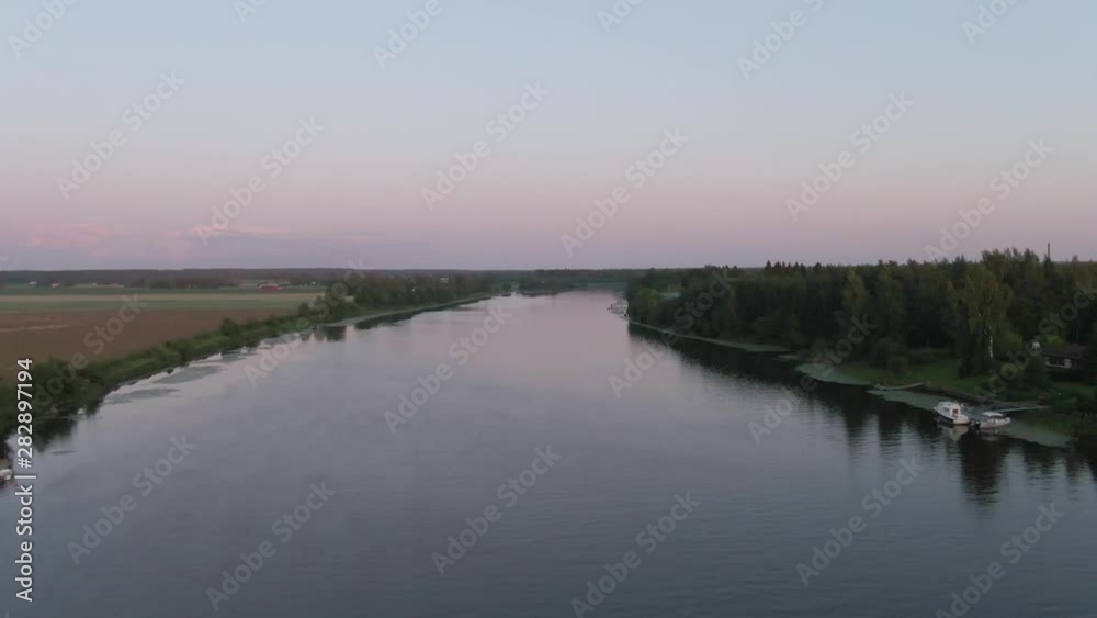 Flying over river with boats and village. Arial drone shot. Water. Ripples and waves. Coast and wild forest. Flying over river with boats and village. Arial drone shot. Water. Ripples and waves. Coast and wild forest.