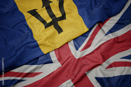 waving colorful flag of great britain and national flag of barbados.