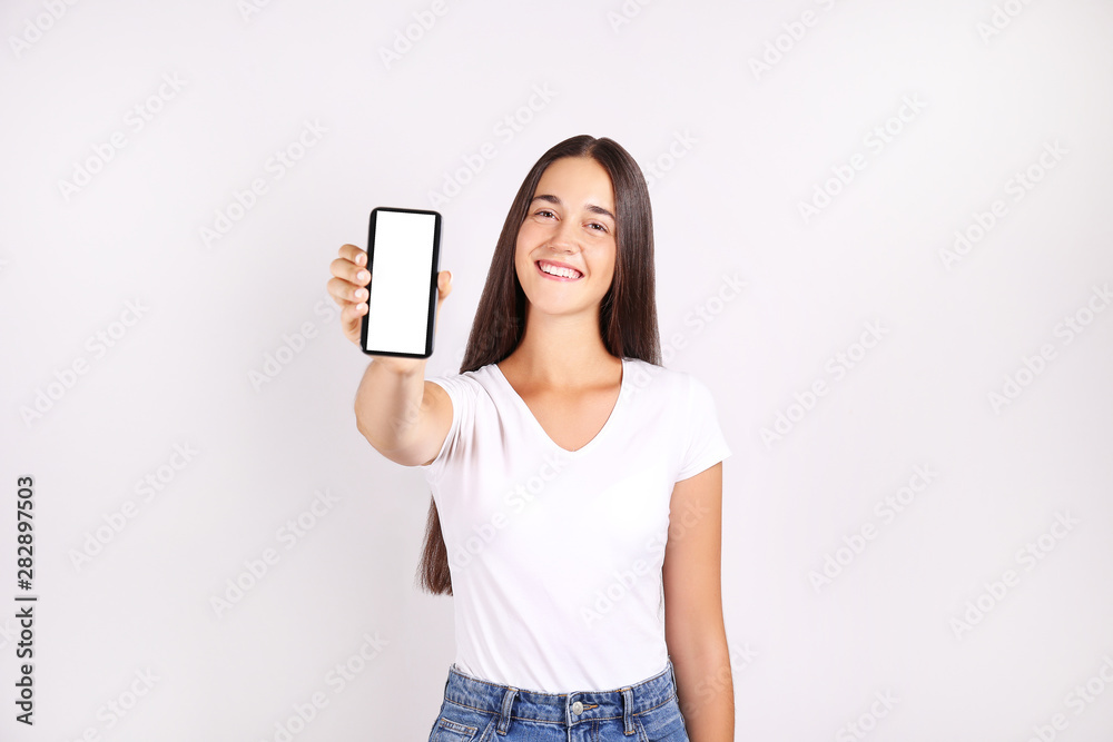 Young beautiful brunette woman w/ long black straight hair posing over bright colorful isolated background & holding smartphone. Portrait of teenage female model showing emotions. Close up, copy space Young beautiful brunette woman w/ long black straight hair posing over bright colorful isolated background & holding smartphone. Portrait of teenage female model showing emotions. Close up, copy space