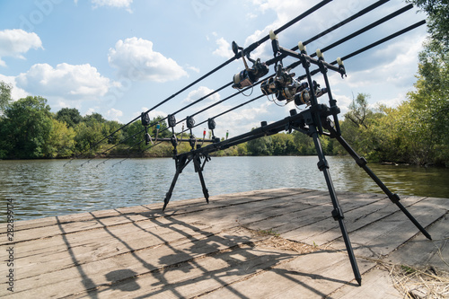 Carp fishing, rodpod with fishing rods on a wooden platform on the lake photo